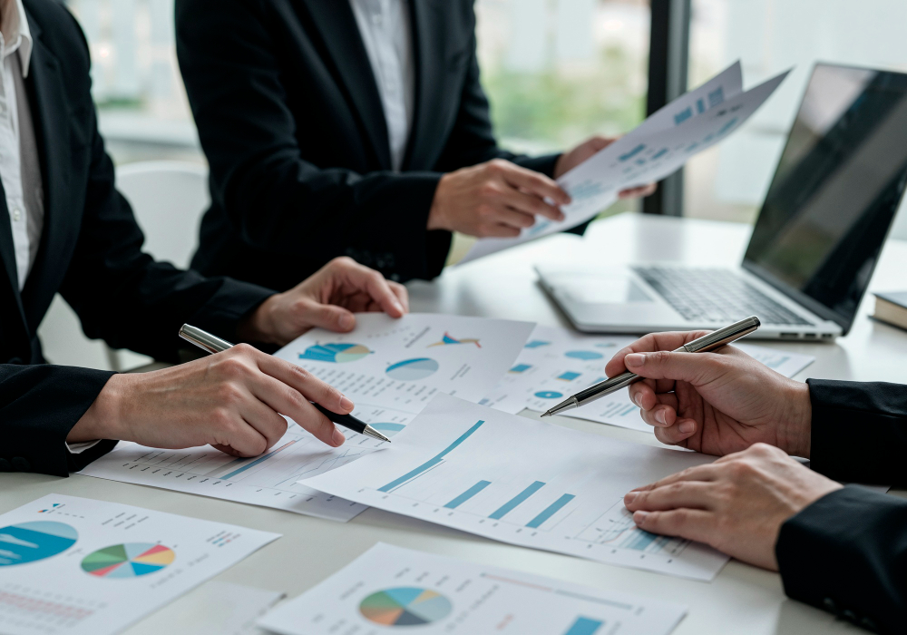 Internal Audit professionals reviewing financial reports and charts in a corporate meeting, analyzing business performance and data insights.