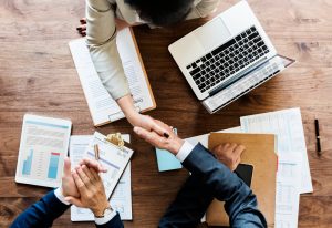 Business professionals shaking hands over financial documents and reports during a corporate meeting, representing compliance with UAE Transfer Pricing Laws, tax documentation, and strategic business planning.