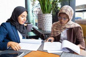 Two business professionals reviewing financial documents and discussing reports in a modern office setting, representing Accounting in UAE, financial record management, compliance, and business advisory services.