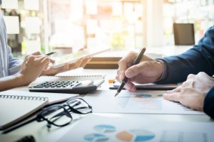 Finance professionals reviewing financial reports, charts, and accounting records during a business meeting to identify and prevent Accounting Mistakes UAE, ensuring accurate reporting, compliance, and better financial decision-making.