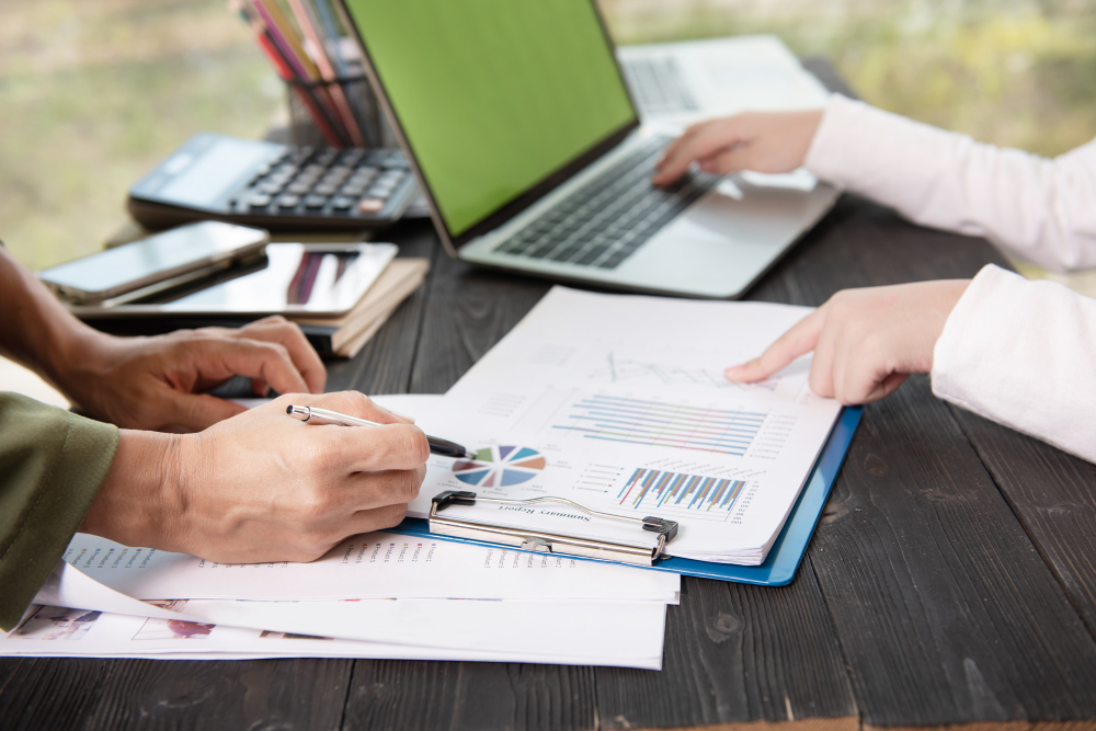 **Alt Text:** Business professionals reviewing financial reports and performance charts during a meeting, illustrating **External vs Internal Audit in UAE** for financial compliance, risk assessment, and effective business governance.